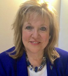 Esposito-Visgitis is pictured in a royal blue blazer with a white shirt underneath. She is smiling at the camera.